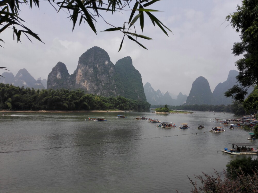 黄布倒影是漓江精华中的精华,也是20元人民币的背面景色。位于漓江精华段兴坪古镇境内,船行其中,江面开阔,水平如镜,青峰倒影,非常美丽。拿出一张20元的人民币与其合影,可以说是件非常有仪式感的事情。游人可以乘船游览,也可以在兴坪古镇内步行远观。 关于黄布倒影的由来倒是有好几种说法,其一是说江底黄沙沉积,像块大大的黄布铺在河床上,所以叫黄布倒影;其二是说透过清澈的江水,可以看见江底有一块米黄色的大石板,就像一块崭新的黄布;其三是说黄色的山壁倒映在水中,好似一匹染过的黄布。不论是什么成因,都为黄布倒影的美丽增