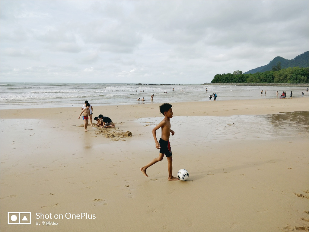 阴天下的海滩,游客在游泳,小孩在玩泥沙,心情很舒心.