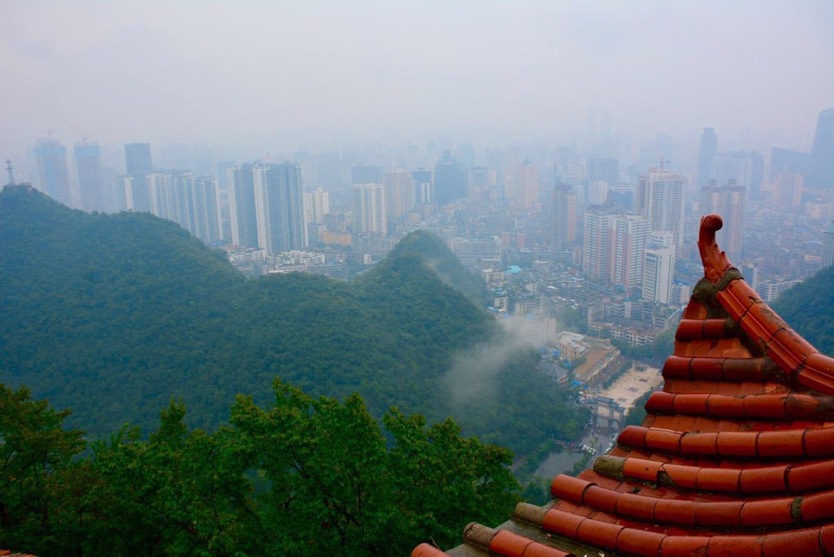 当地人称的整个贵州最具性价比的公园,门票只要5元。上午小雨。酒店出门左转过一个地道,就能看到南大门。坐索道上山,15元一人。贵阳简称筑,顾名思义,登上瞰筑亭即可俯瞰整个贵阳城。身在高处看群山环抱中贵阳城,雨雾中高楼林立,倒比在平地上近看时美了许多,朦胧美。下山时先到弘福寺,香火很旺,正有和尚香客在一起诵经做供斋。此时雨渐渐转大,担心看不到猕猴。在下山路上继续走了好一阵,忽然有三两只猕猴从树上跳下来向我们走来。一只小猴子目标非常明确,伸手就抓我们手中的塑料袋。那是特地为了喂猴子带的葡萄。结果一惊袋子整个被