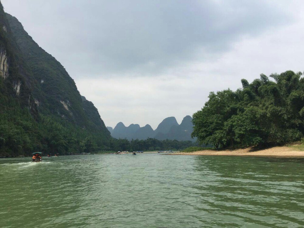 黄布滩之所以如此开名,因为这里江流清澈,碧绿透底,从水面上可以看到江底有块米黄色的大石板,似一匹黄布而得名。它与刚刚的九马画山旁边的朱壁滩之间,有7座大小不一的山峰,亭亭玉立,宛如7位浴水而出的少女,习称七仙女下凡。据说在晴天无云的日子里,山水连成一片,令人分不清水上青山和水中倒影,于是形成了如此有名的黄布倒影的景致。但这里游船星罗棋布地分散在江面各处,实在无办法能欣赏平静江面的倒影的美,更不用说黄布倒影了。建议一大清早来到此地,或淡季之时才能看到那种让人叹为观止的美景。