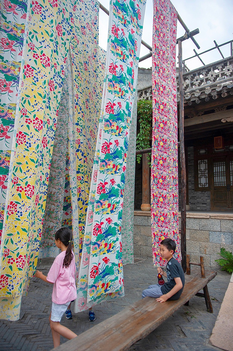 位于北京古北水镇内的的永顺染坊,有一大片晒布场,高高挂起的大块花布